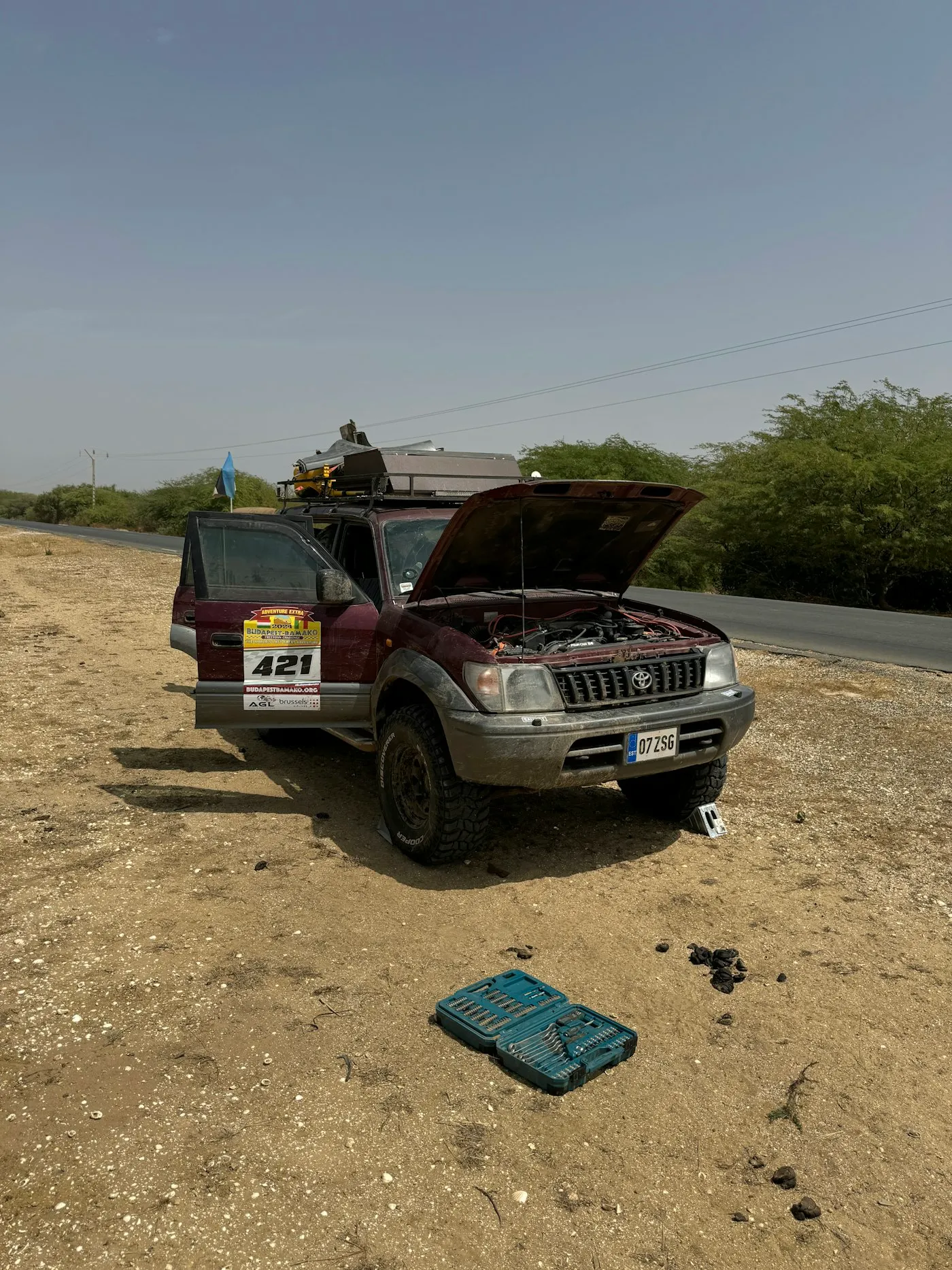 A stranded vehicle on the roadside with its hood open